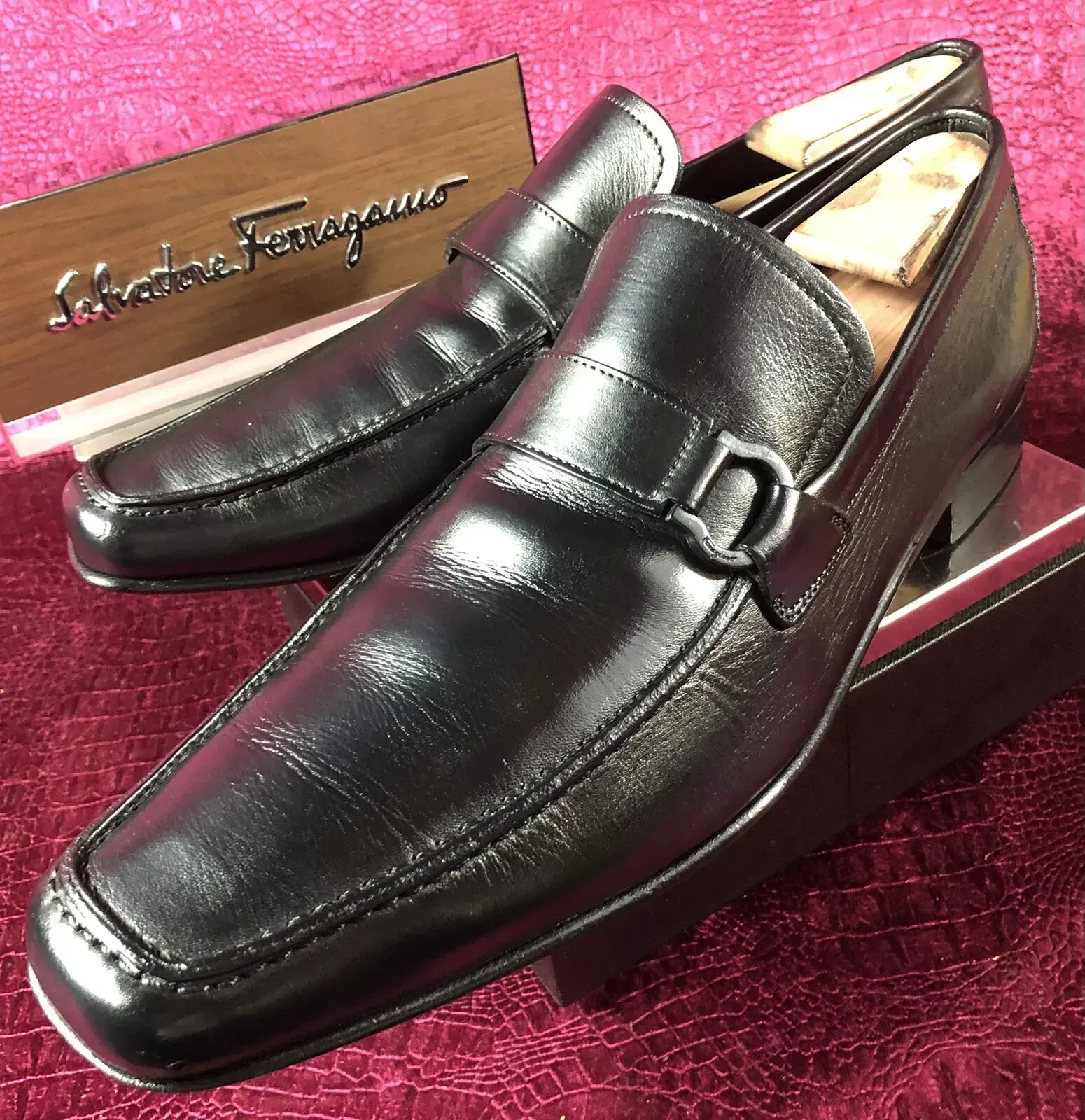 A pair of black ferragamo shoes sitting on top of a box