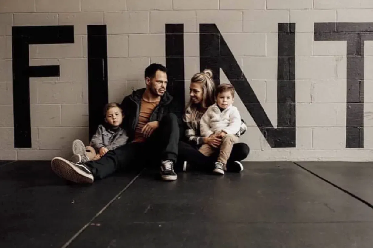 A family is sitting on the floor in front of a wall with the word flint painted on it.