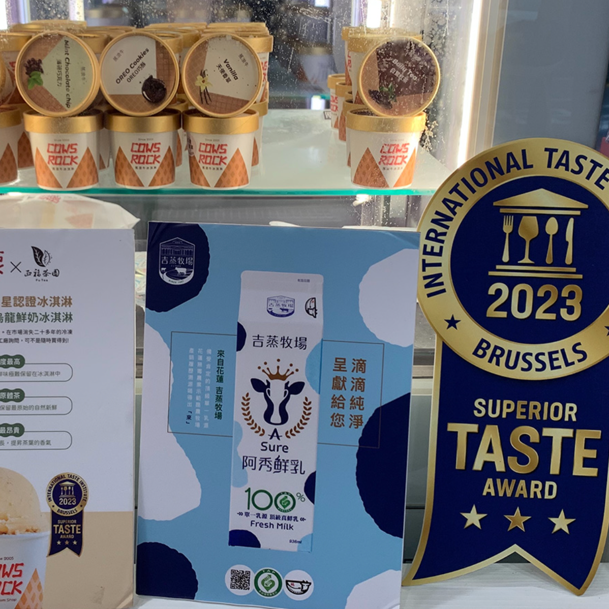 前面的宣傳品上寫著「Superior Taste Award」，後面冰櫃有一排乳製品