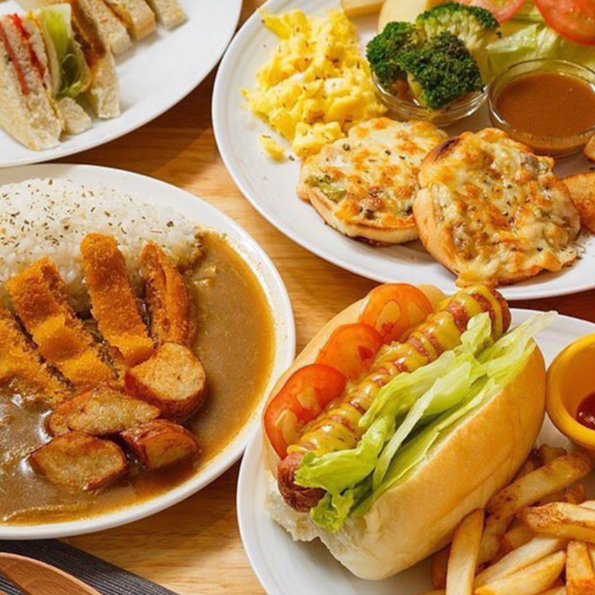 桌上放著一堆食物，有咖喱飯、煎餅和熱狗堡