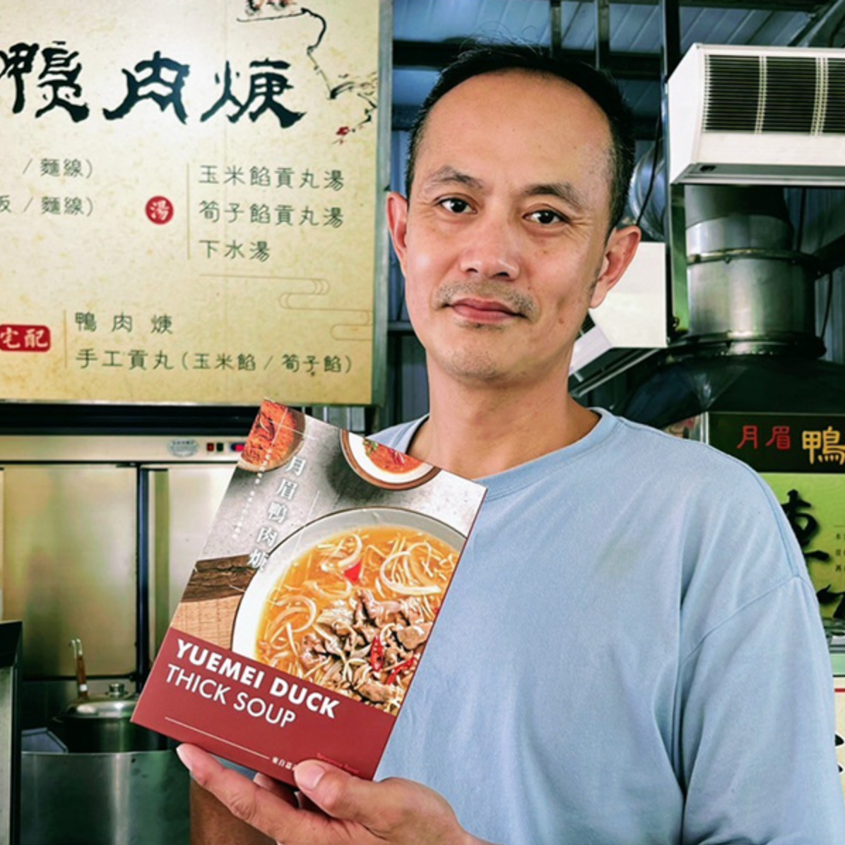 一位男性拿著一盒月眉鴨肉羹料理包