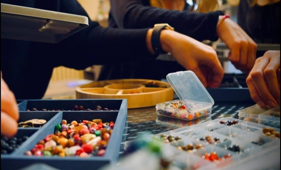 A group of people are working on a project with beads