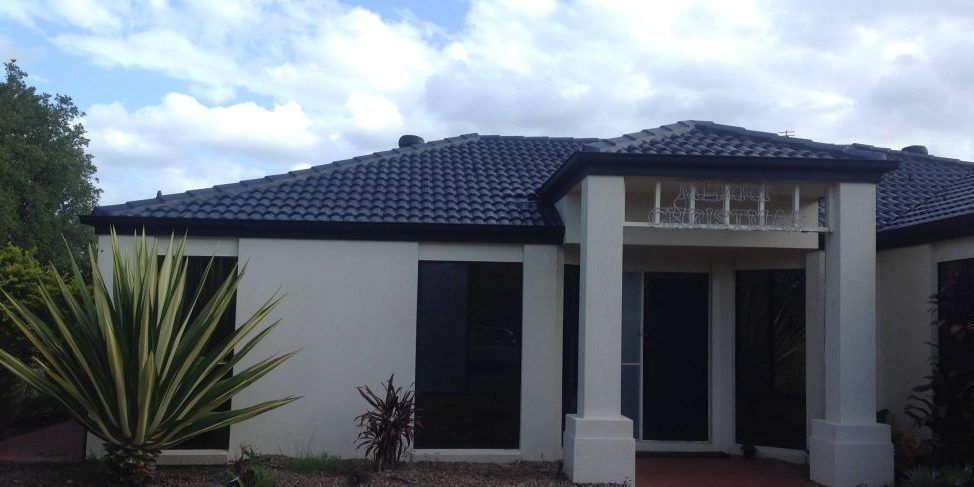 A white house with a black roof and a porch