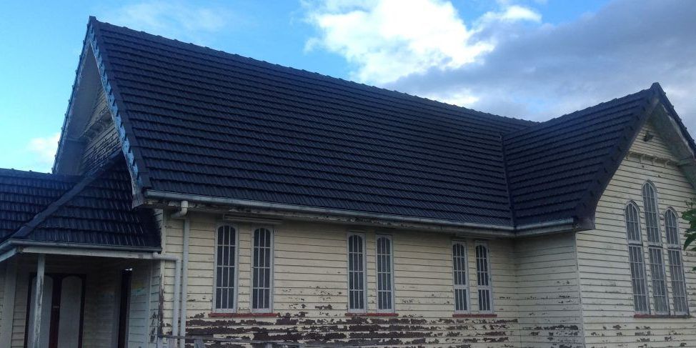 A white house with a black roof and a blue sky in the background.