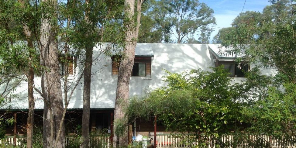 A white house is surrounded by trees on a sunny day.