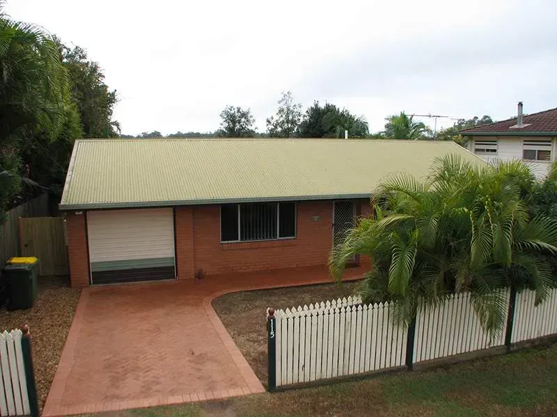 A brick house with a white garage door and a white picket fence