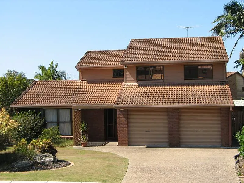 A brick house with a brown roof and two garage doors
