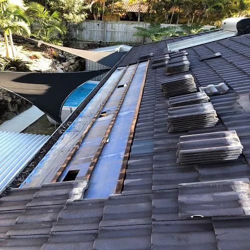 A roof with a lot of tiles on it and a pool in the background.