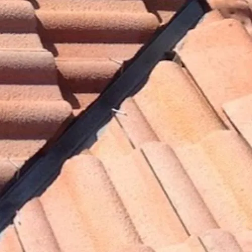 A close up of a tiled roof with a black gutter.