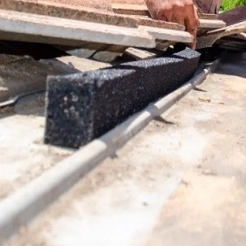 A person is laying bricks on a roof.