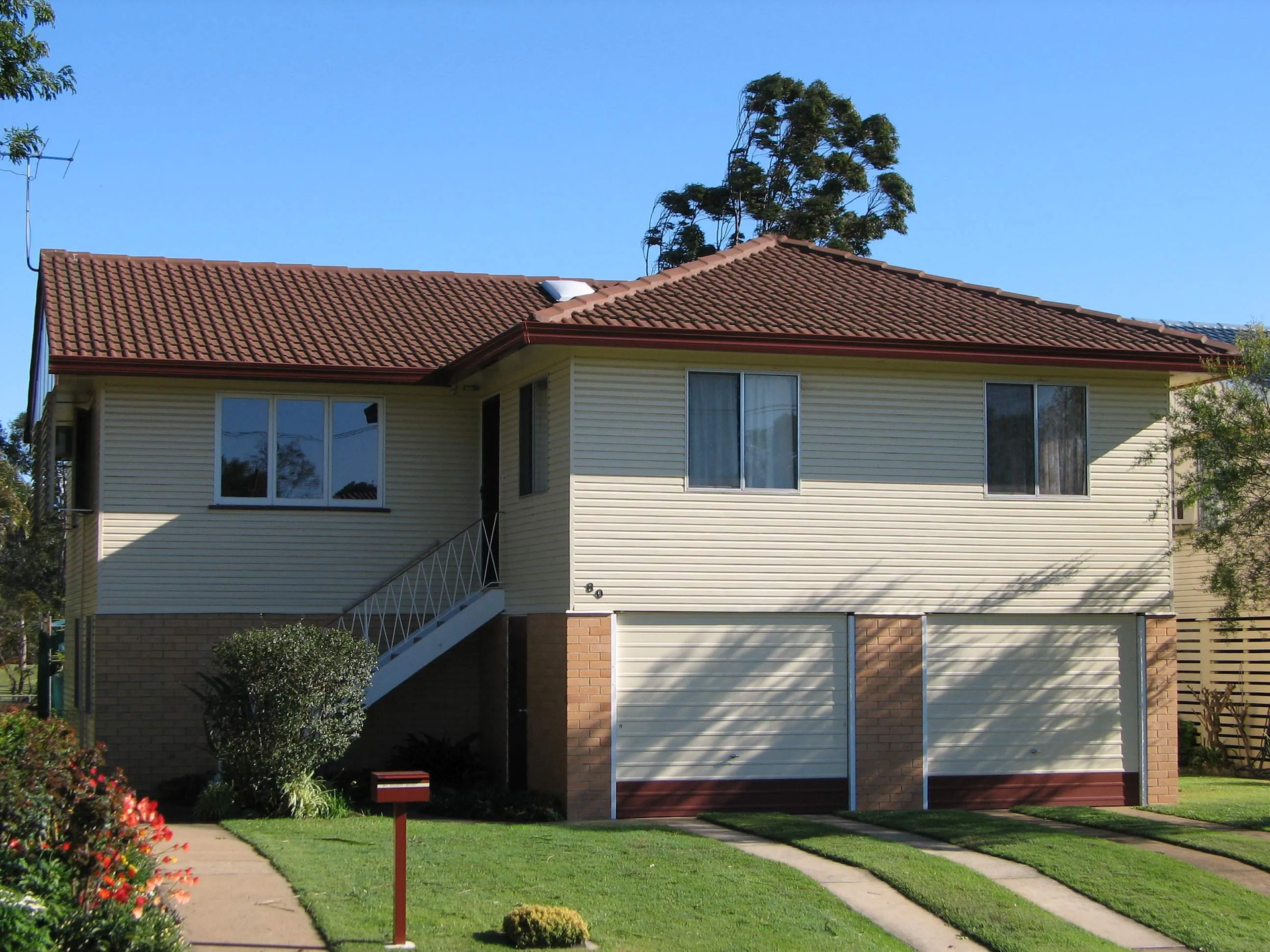 A white house with a brown roof has a mailbox in front of it