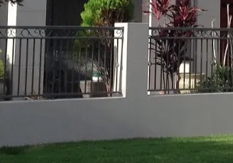A fence surrounds a lush green lawn in front of a house.