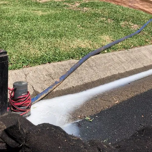 A hose is being used to spray water on a sidewalk.