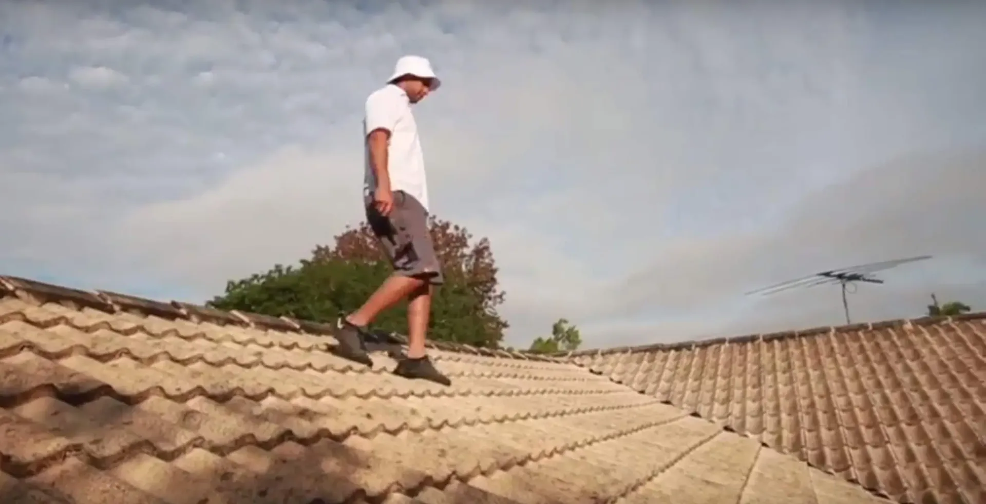A man is walking on the roof of a building.