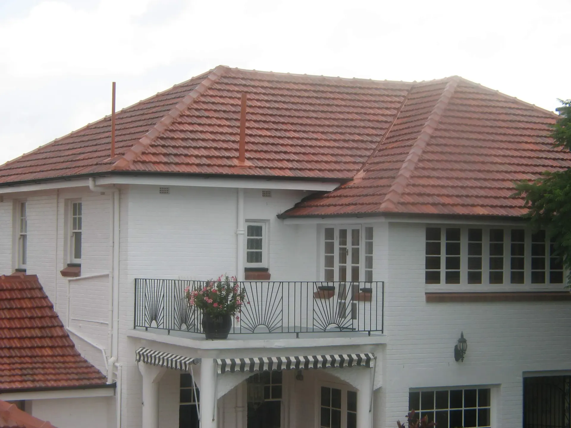 A white house with a terracotta tiled roof after a roof restoration