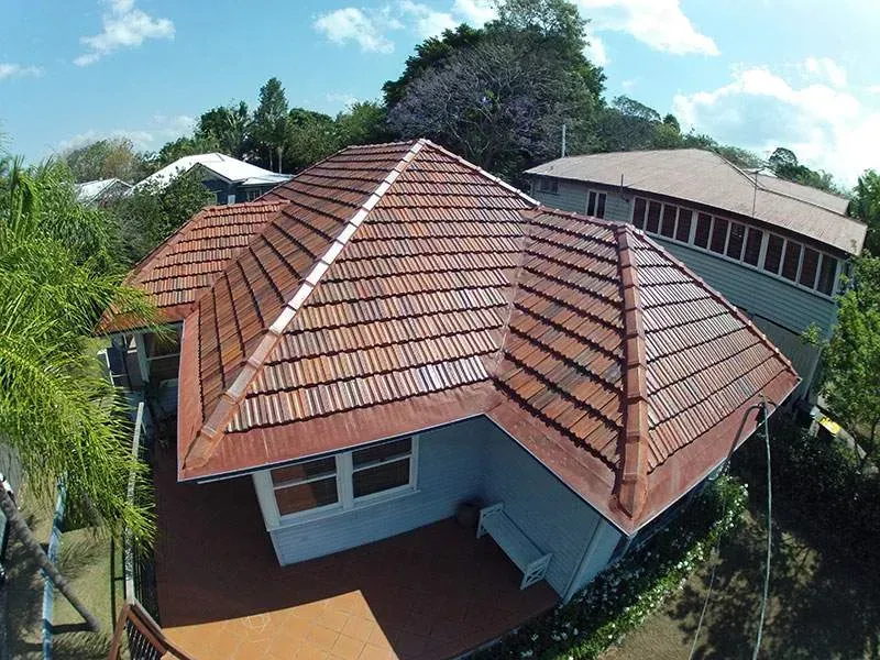 An aerial view of a house with a tiled roof surrounded by trees.