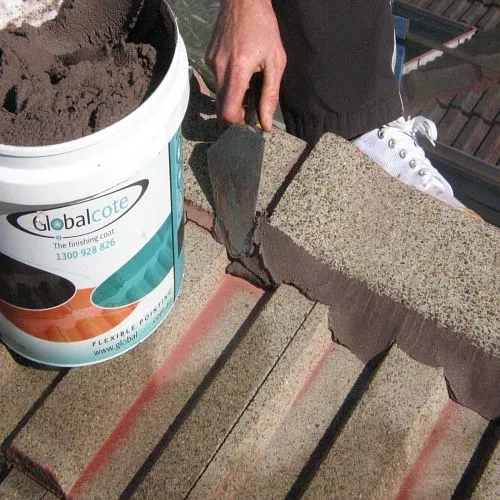 A bucket of globalcote is next to a person using a spatula