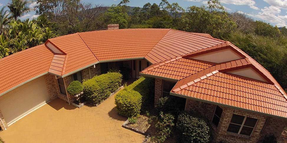 An aerial view of a house with a red tiled roof surrounded by trees.