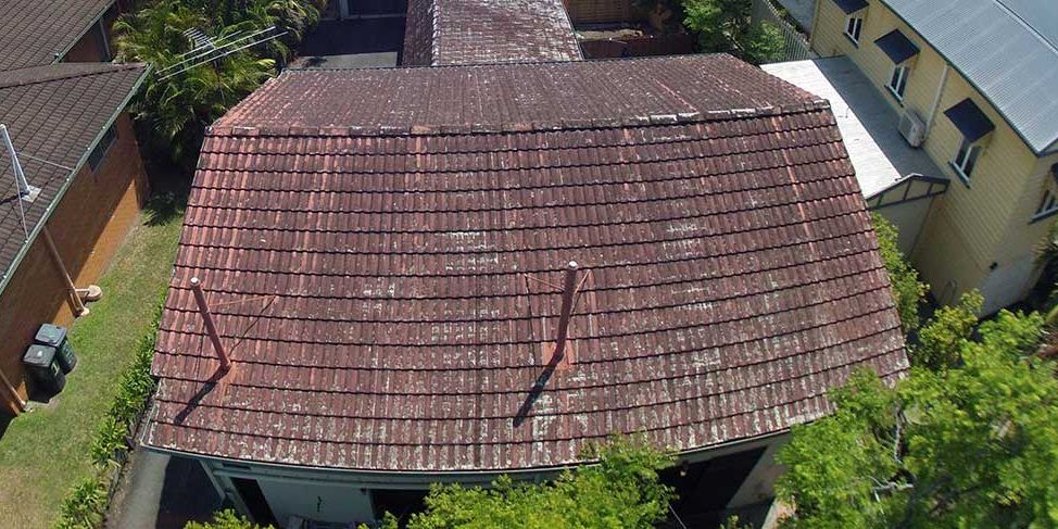 An aerial view of a house with a tiled roof surrounded by trees.