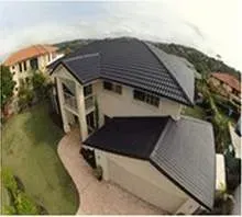 An aerial view of a large house with a black roof.