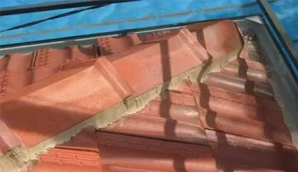 A roof with red tiles and a blue tarp on it.
