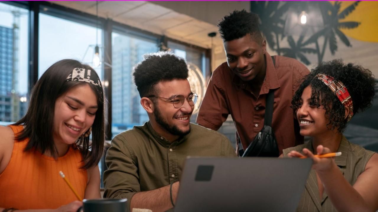 Grupo de pessoas sentado ao redor de uma mesa olhando para um laptop simulando um site para ONGs