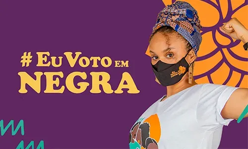 Uma mulher usando máscara e turbante está em frente a um fundo roxo.