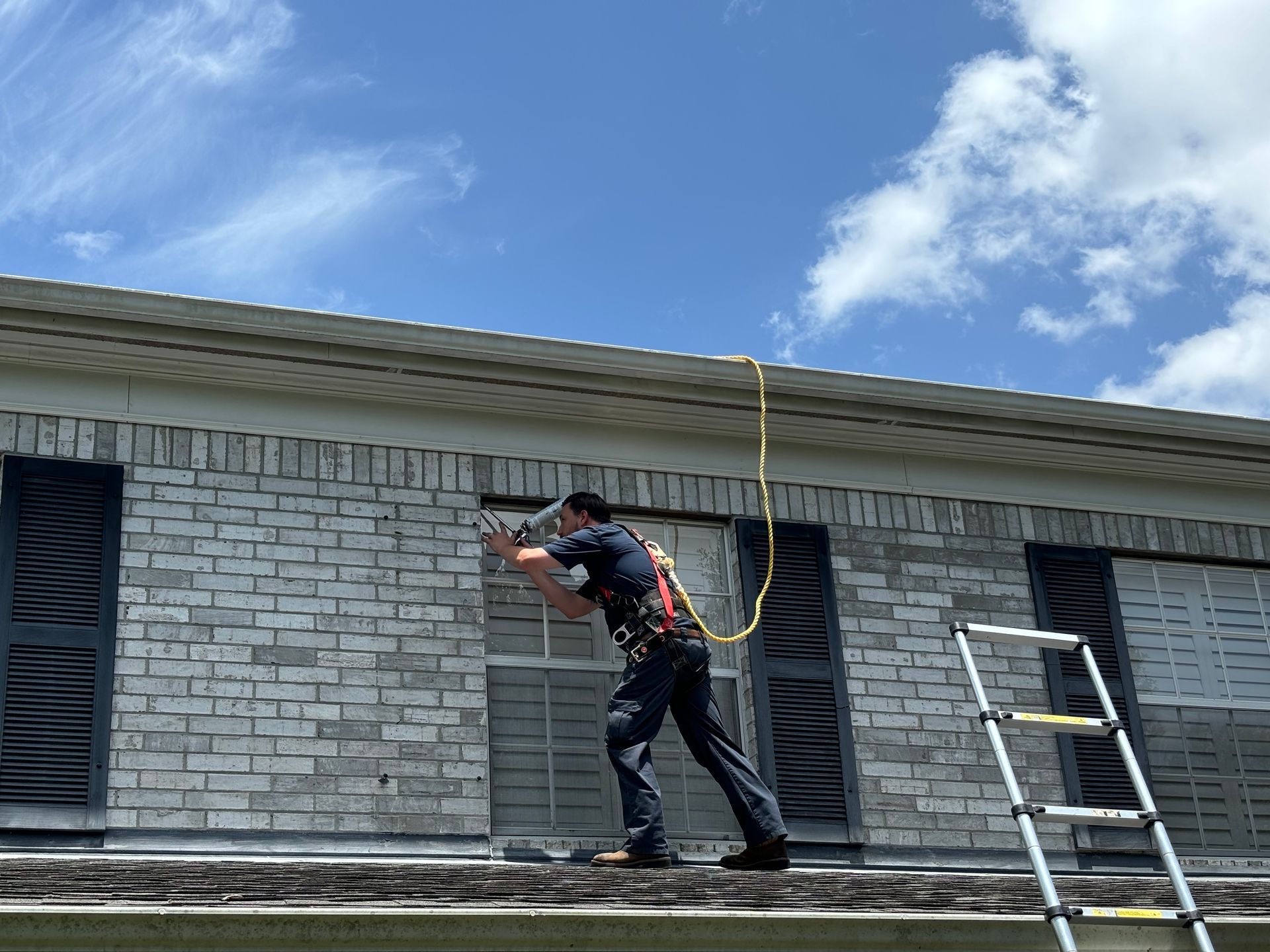 Technician on a roof sealing a window from rats.