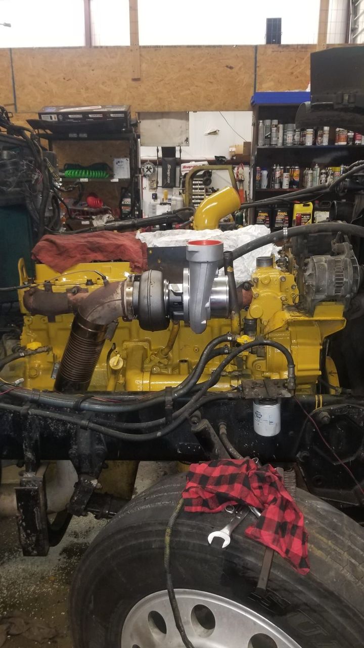 A yellow engine is sitting on top of a truck in a garage.