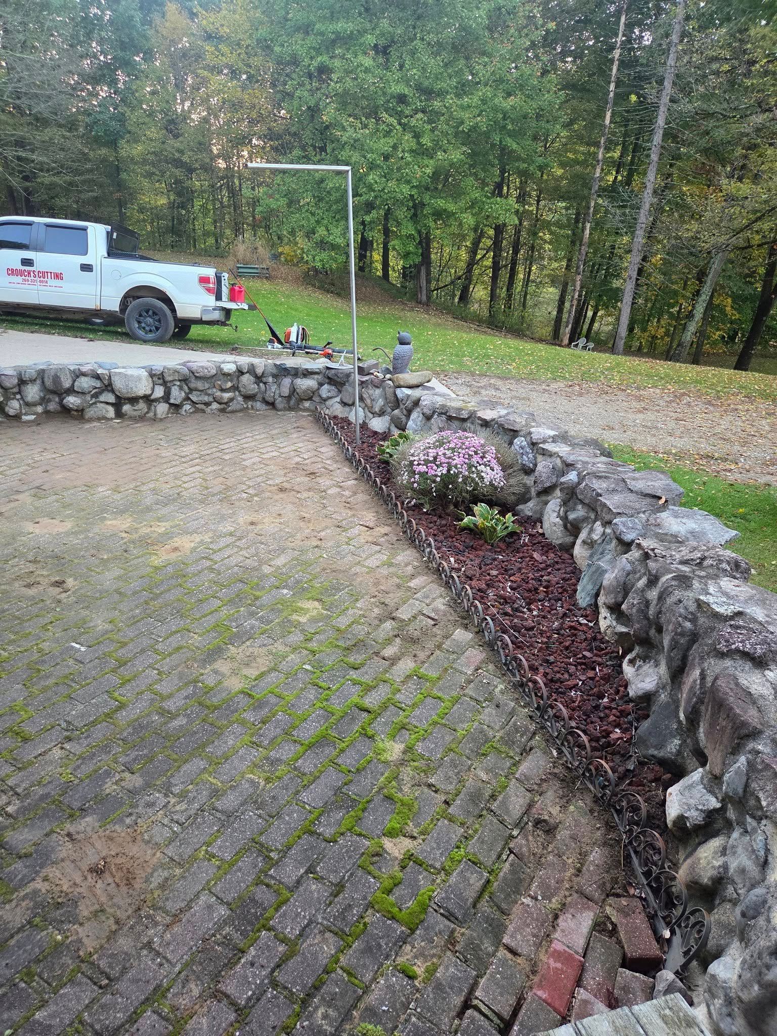 Truck loading a large pile of brown leaves beside a road on a cloudy day. Houses in the background.