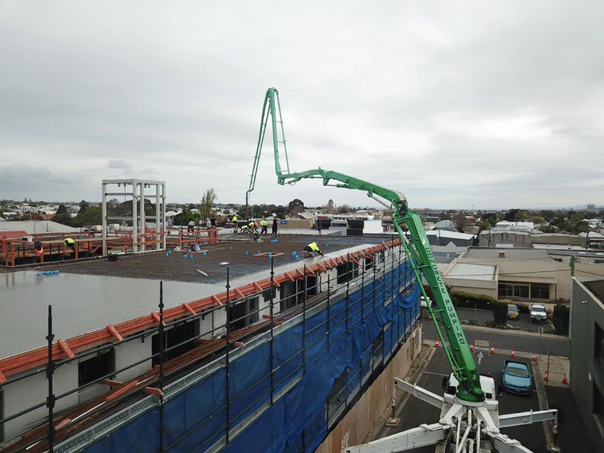 An aerial view of a building under construction with a green crane.