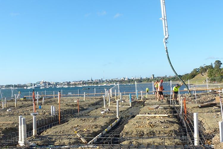 A group of people are working on a construction site next to a body of water.