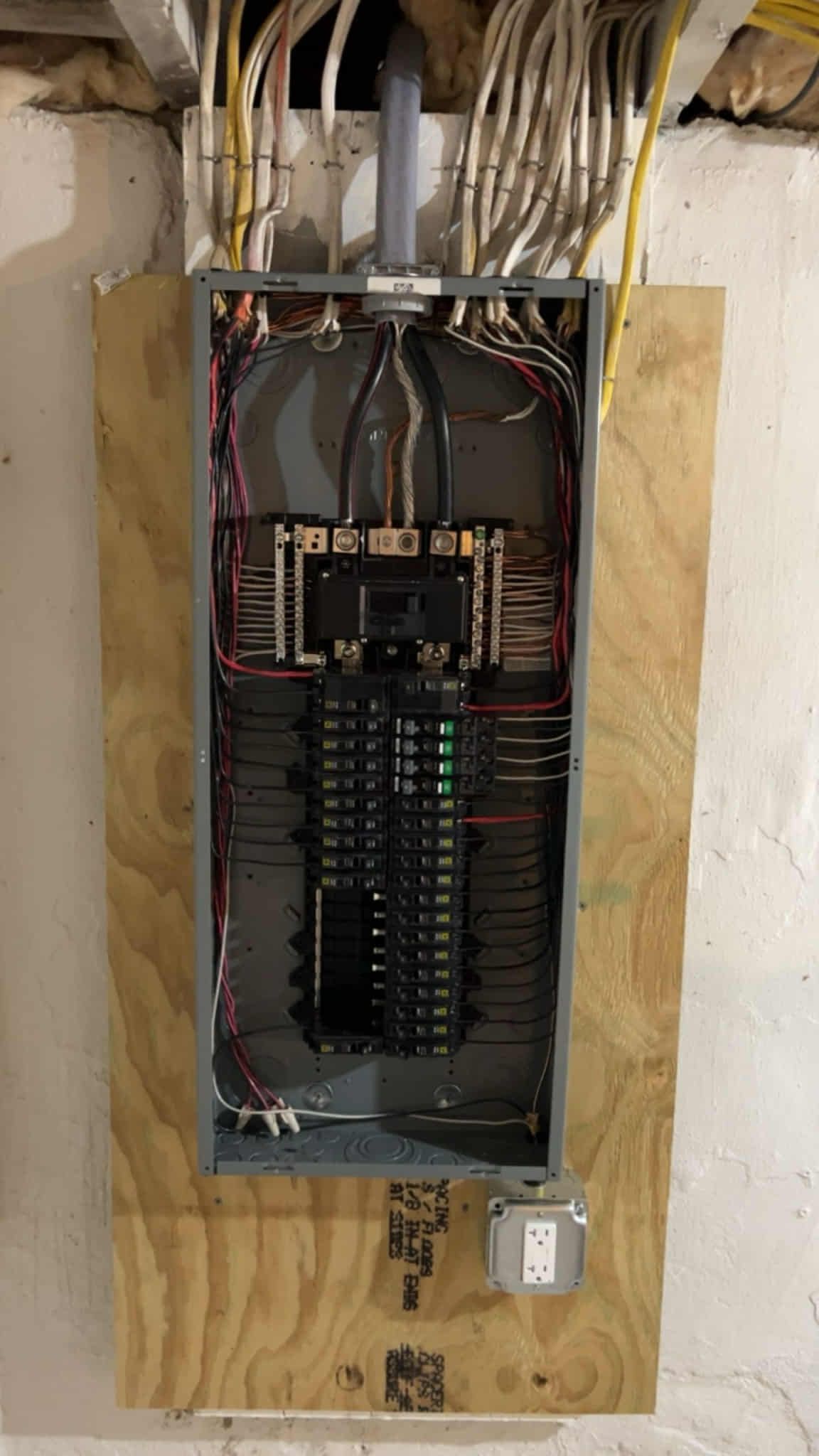 Electrical panel with breakers and wires in a wall.