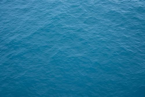 A top-down view of calm, deep blue ocean water with gentle ripples across the surface.
