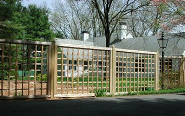 A wooden fence in front of a house with trees in the background