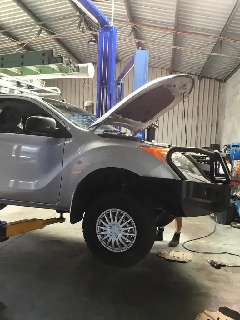 A Car is Sitting on a Lift in a Garage With the Hood Open — Auto Repair Solutions Unanderra In Unanderra, NSW