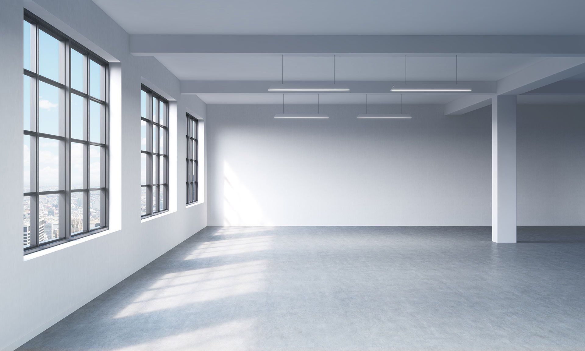 Empty, sunlit room with large windows and concrete floor. White walls and support beams, minimalist.