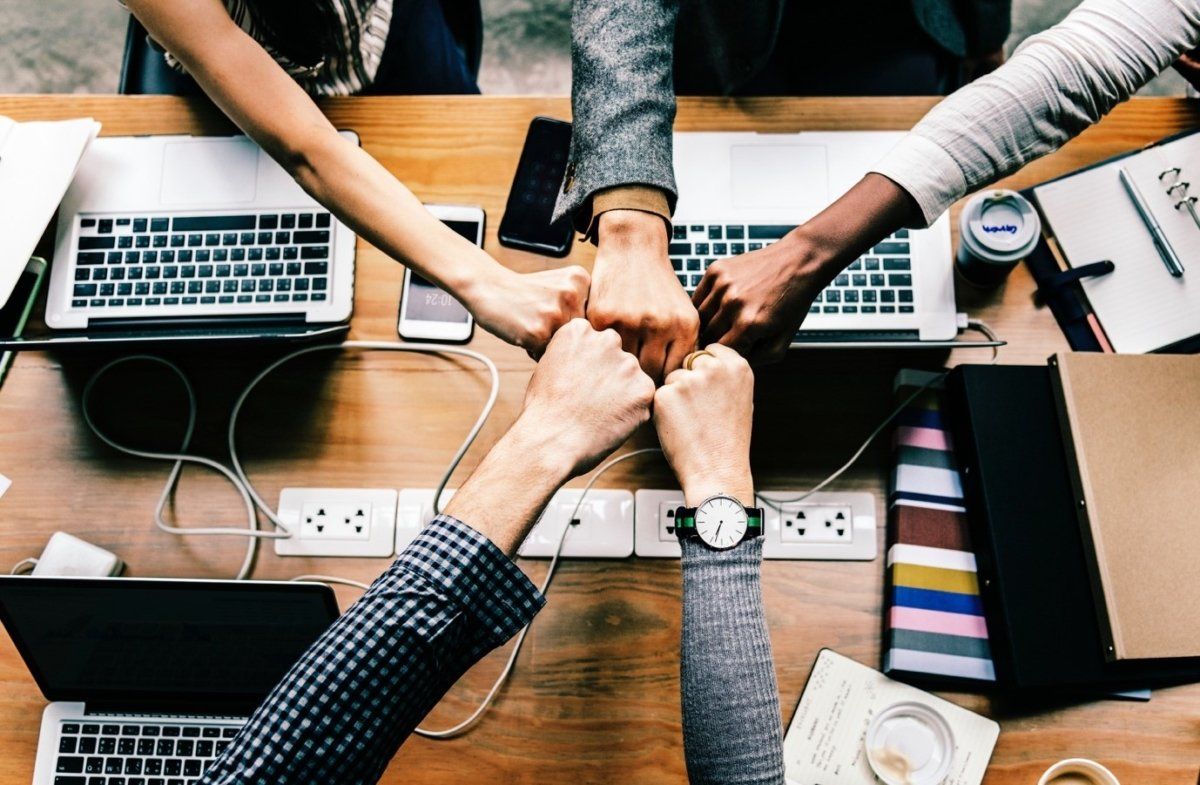 A group of people are putting their hands together in a circle.