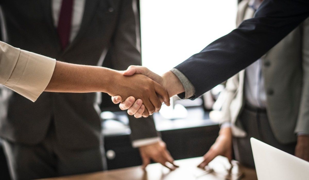 A group of business people are shaking hands over a table.