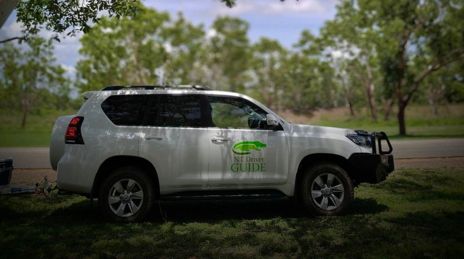 White SUV parked on grass with trees in background — NT Driver Guide - Escorted Tours & Transfers in Darwin City, NT