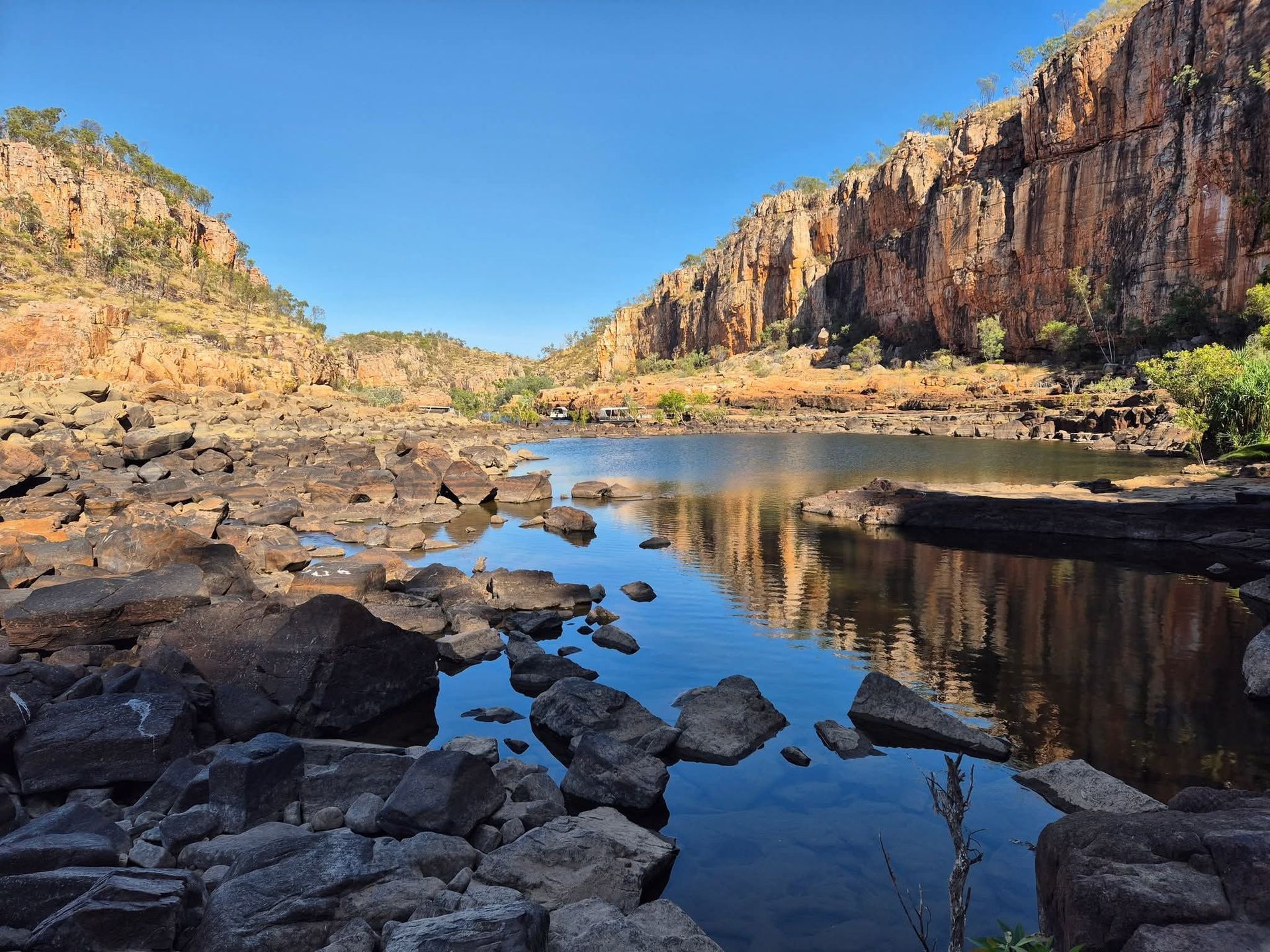 Scenic view of a water-filled gorge with rocky shores and towering cliffs under a clear blue sky — NT Driver Guide - Escorted Tours & Transfers in Darwin City, NT