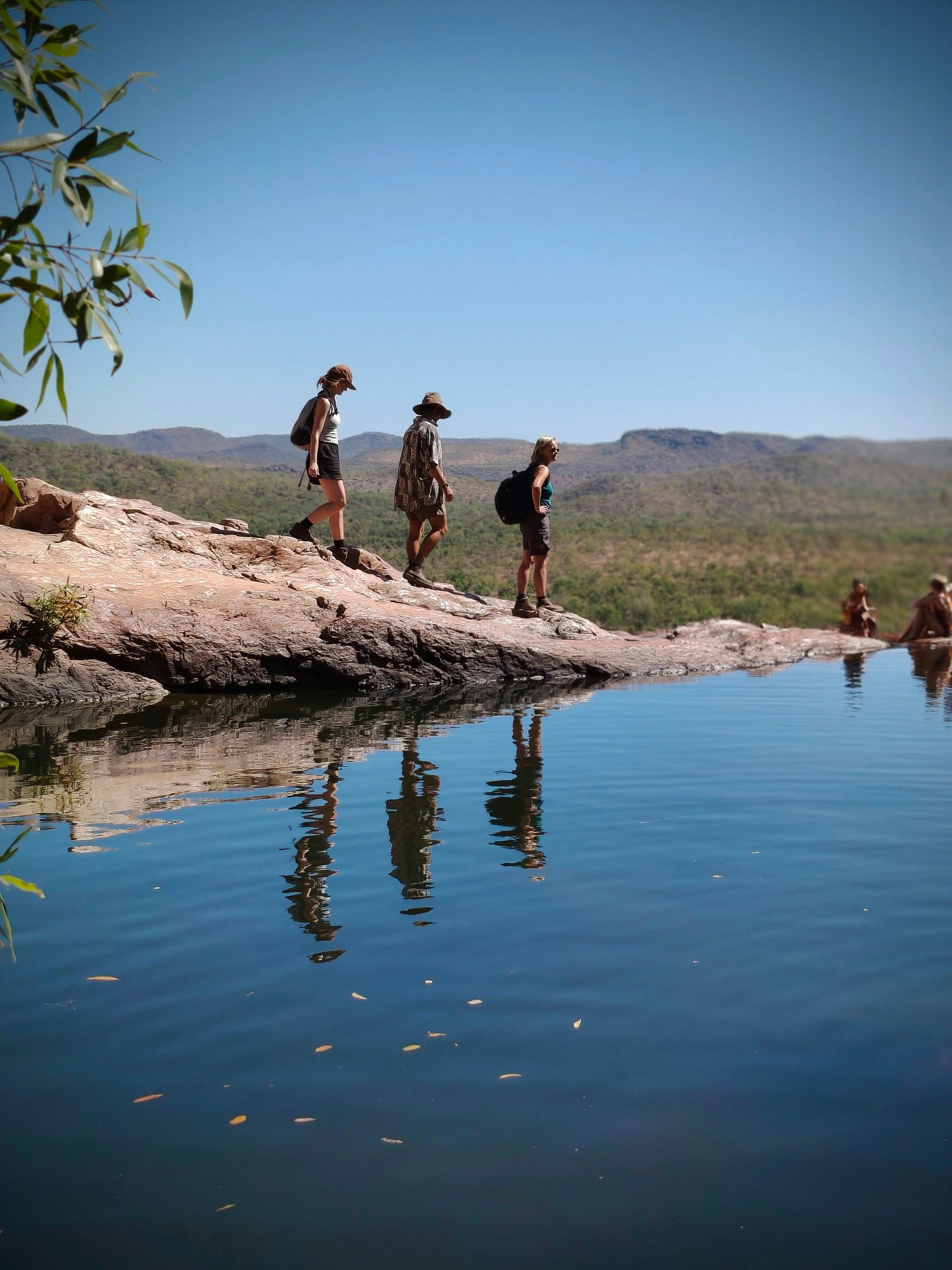 People stand at edge of a natural pool overlooking a vast landscape on a bright day — NT Driver Guide - Escorted Tours & Transfers in Darwin City, NT
