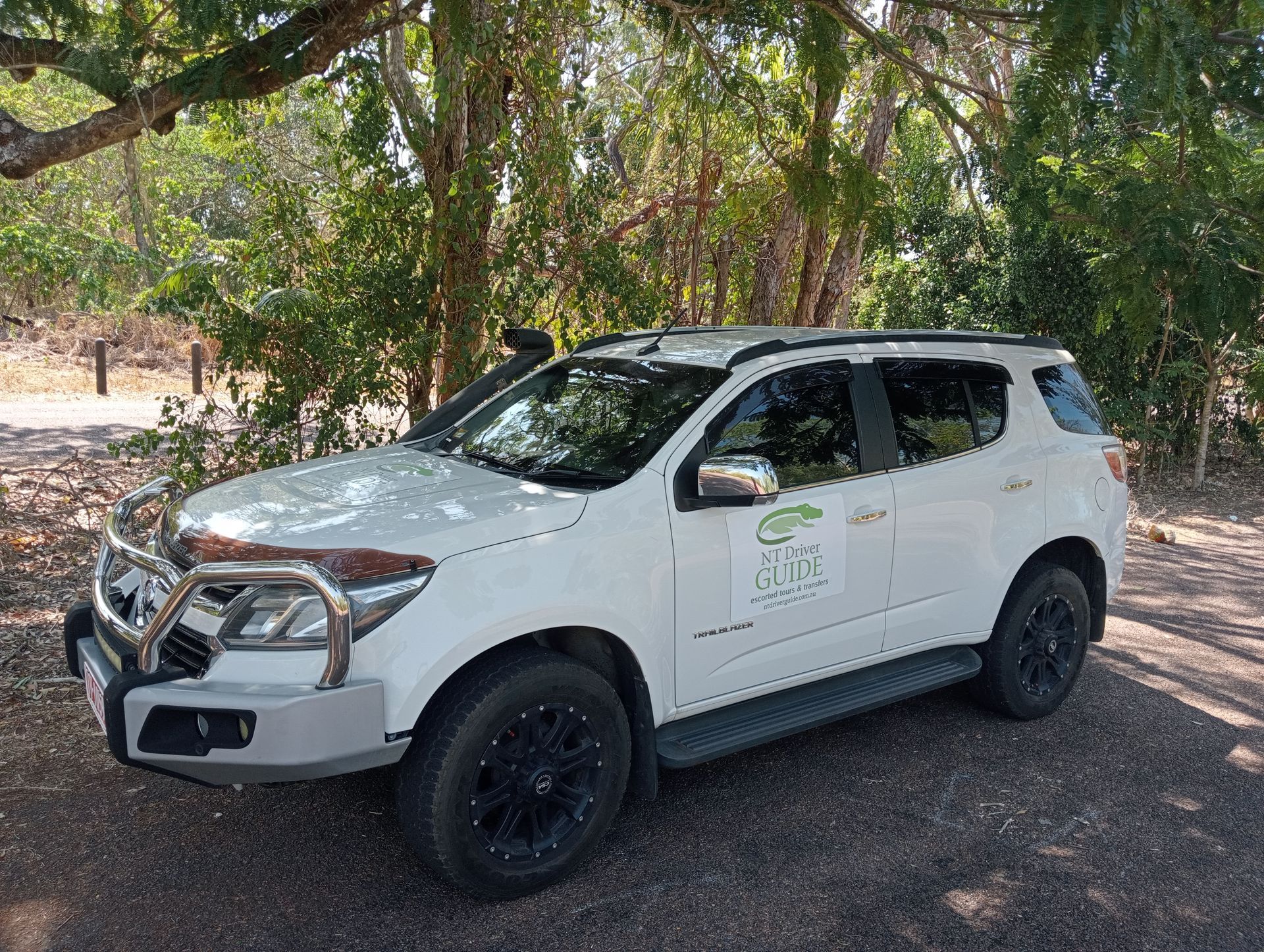 A White SUV is Parked Under a Tree on a Dirt Road  — NT Driver Guide - Escorted Touring & Transfers in Darwin City, NT