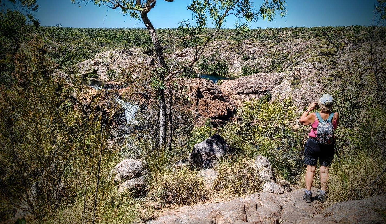 Couple seated on a green airboat. Woman in patterned skirt, man in plaid shirt, both wearing headphones. Outdoors, sunny  — NT Driver Guide - Escorted Tours & Transfers in Darwin City, NT