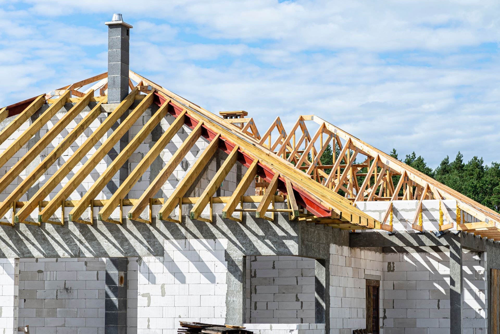 Wooden roof trusses without roofing or shingles, on top of a house in construction.