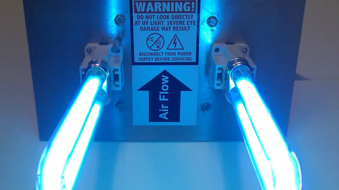 Blue UV light air sanitizer with warning label and air flow arrow. JL Mechanical - Heating & Cooling