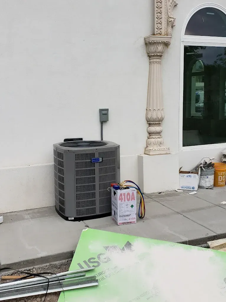 AC unit next to a white wall and column during construction, with construction materials visible. JL Mechanical - Heating & Cooling