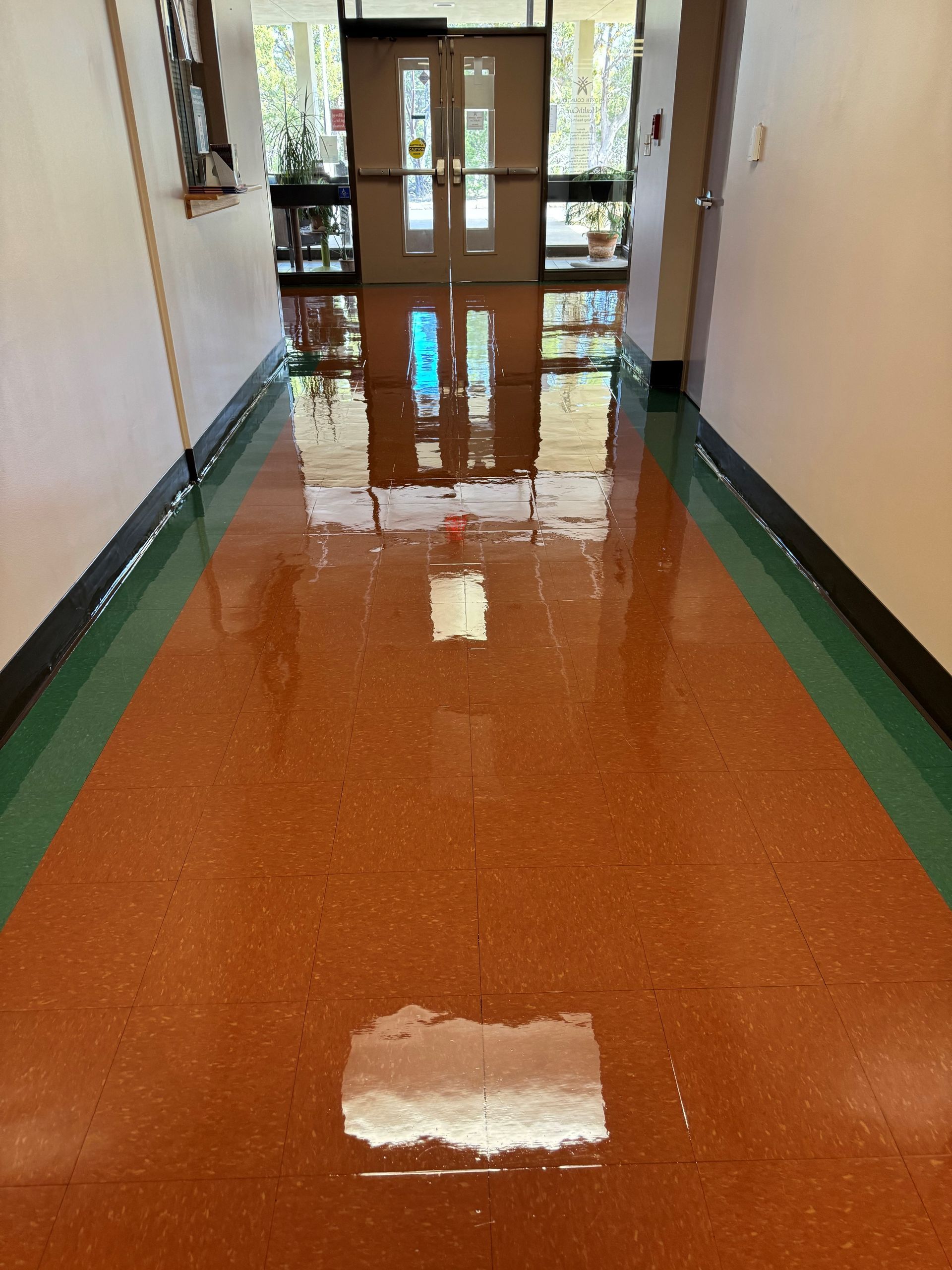 A hallway with a reflection of a door in the floor