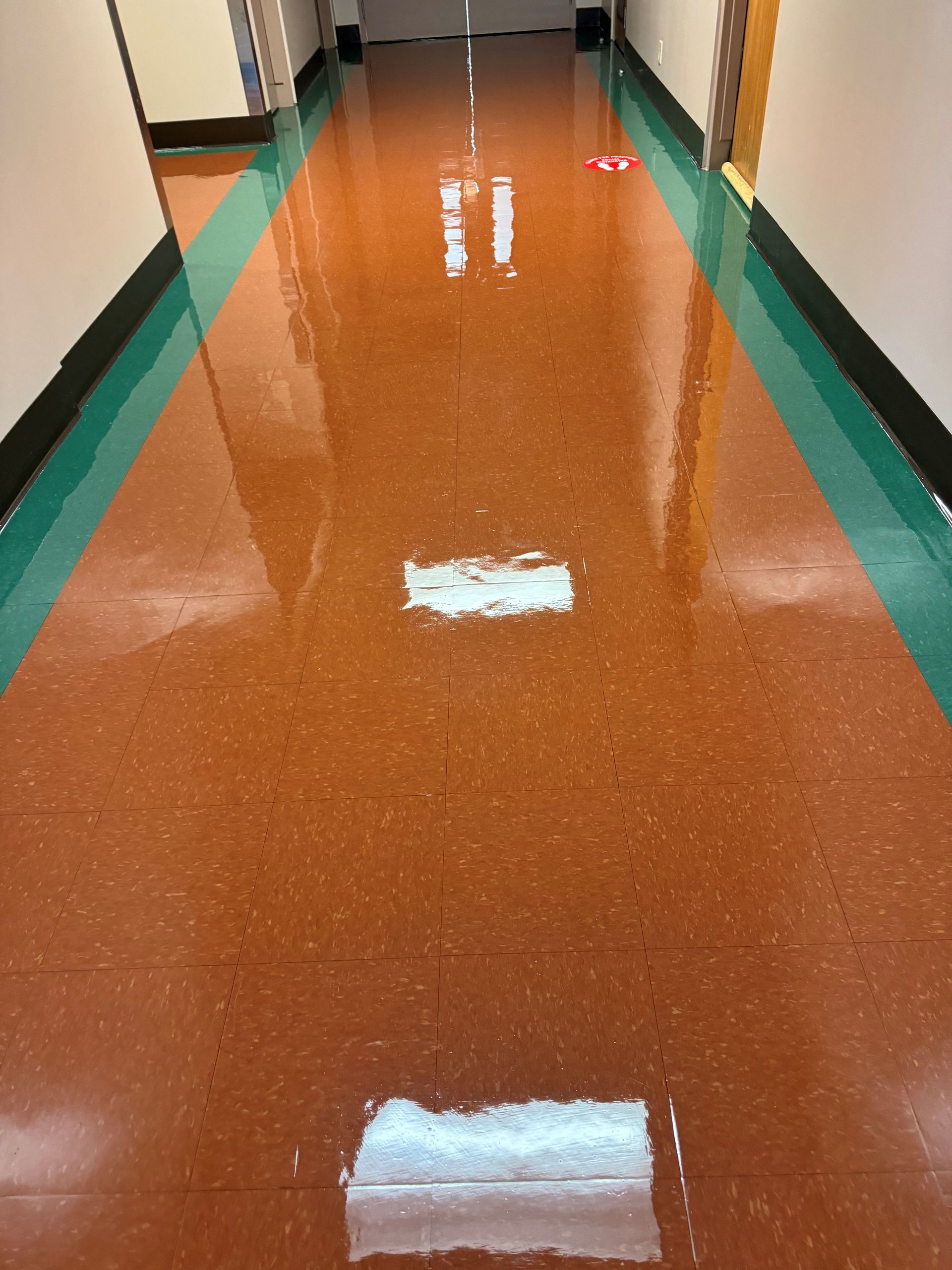 A hallway with a red tile floor and green borders