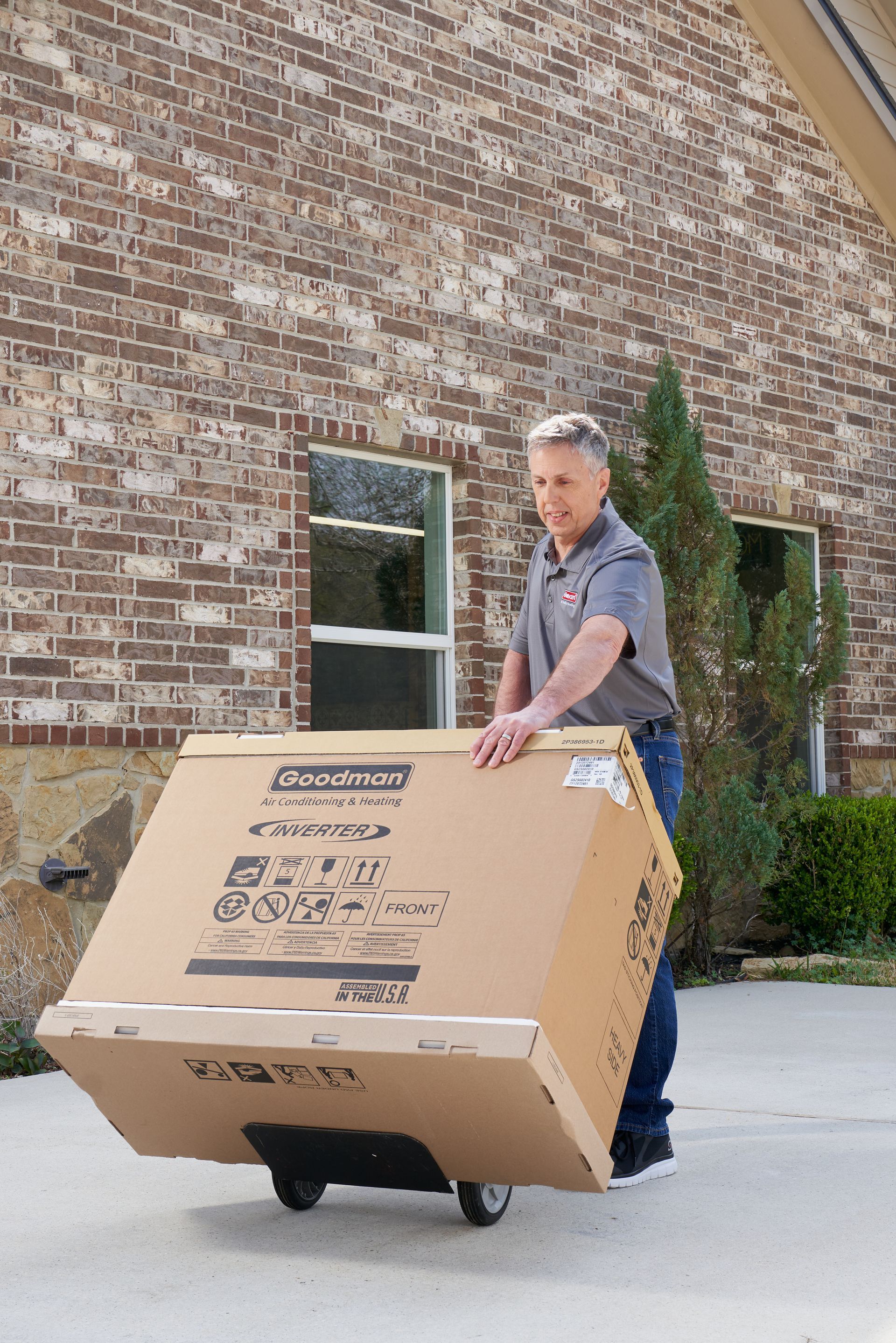 A man is carrying a side discharge AC on a dolly.